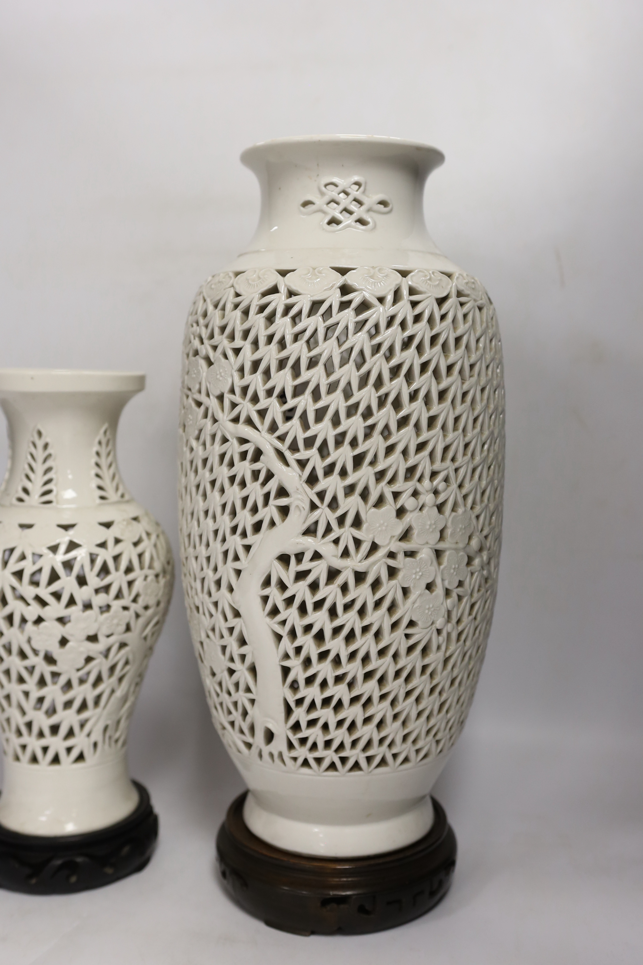 Two Chinese blanc de chine reticulated vase/lamps, on carved stands, largest 40cm high